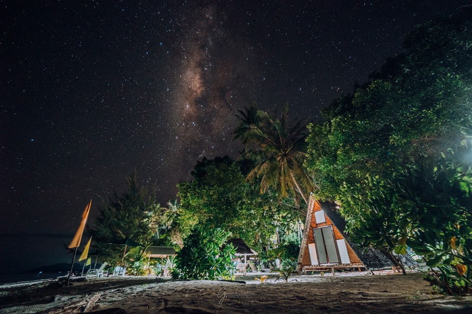 Guests gathered around a beachfront bonfire at night